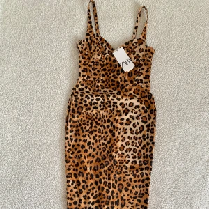 ZARA midiklänning i leopardmönster med korsett - Leopardmönstrad korsettklänning i midilängd från ZARA med slits där bak, satinklänning. Sjukt SNYGG. Ny med prislappar. Ordinariepris 559kr. 