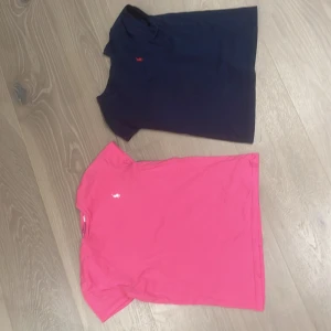 Två t-shirts från Ralph Lauren - Säljer två snygga t-shirts från Ralph Lauren. Den ena är mörkblå och den andra är rosa, båda med det klassiska Ralph Lauren-loggan broderad på.