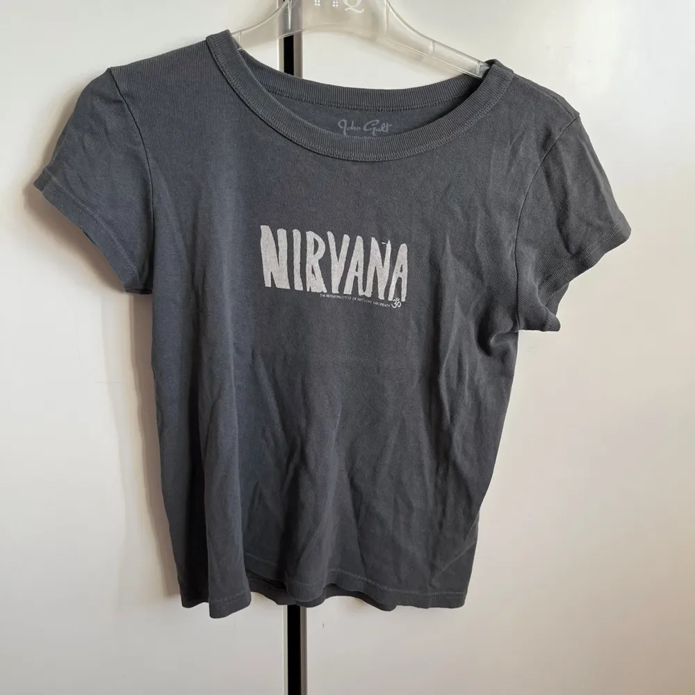 Säljer en grå Nirvana t-shirt från Brandy. Den är kortärmad och har en cool vintage-look med Nirvana-loggan tryckt på framsidan.. T-shirts.