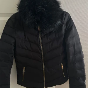 Vinterjacka dam S från H&M - Svart helfodrad vinterjacka från H&M. Jackan har en avtagbar krage i fuskpäls. Är i fint skick. Storlek 36
