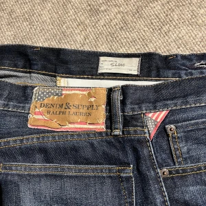 Denim and suply jeans - Säljer ett par jeans från Ralph lauren denim and suply i storlek 31/21. Byxorna är i väldigt fint skick utan några defekter. Färgen är mörk blå trots att den kan se lite svart ut på bilderna.  Slim Fitt, 17cm vid benöppningen