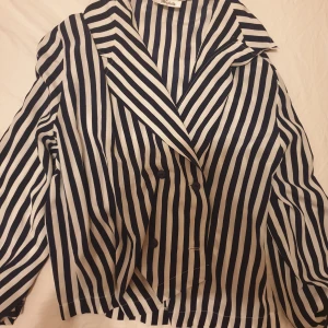 Randig skjorta - En randig skjorta med långa ärmar och knappar framtill. Den har en v-ringning och en lös passform. Säljer för 70