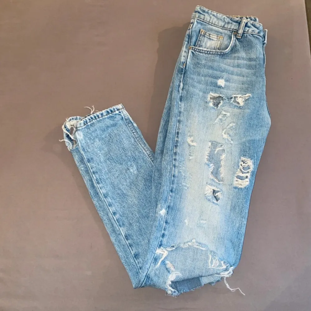 Säljer ett par otroligt snygga blå jeans från never denim i storlek XS. De har en cool sliten look med flera revor och slitningar på framsidan. Har sytt dit en tygbit under rumpan (inget som syns utifrån). Använda men i bra skick. . Jeans & Byxor.