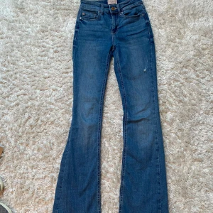 Blå bootcut jeans - Säljer ett par snygga blå bootcut jeans i bra skick, från Vero Moda. Det har en snygg slitning. Perfekta nu till hösten och för både vardag och fest!🤎