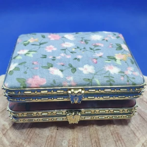 Söt fickspegel - Söt fickspegel med 2 spegelglas. Utsidan har ett mjukt blommigt tyg, knäppet är en liten fjäril och vackra mönster runt spegelglasen. Mått är ca: 7.5 × 6.5 cm. Denna finns i annan form/färg, se mina andra annonser. Perfekt att ha med sej i väskan.