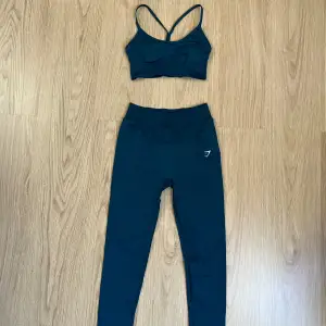 Grönt träningsset med sport-bh och tights från Gymshark. Bra skick, använd få gånger. Färgen heter ”Winter teal” och är grönare i verkligheten än på bilden. Från kollektionen Sweat seamless. Sport-bh:n är liten i storleken. Orginalpris: 1248kr