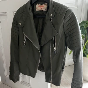 Grön moto jacket - Militärgrön skinnjacka från Chiquelle i strl. 38, i fint skick. Nypris: 599 kr