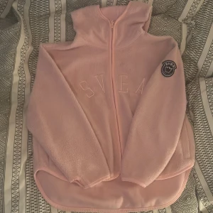 Teddyjacka/tröja från Svea - Jättefin rosa teddy från Svea m luva och fickor som går att stänga med dragkedja. Är knappt använd och väl omhändertagen så är som ny