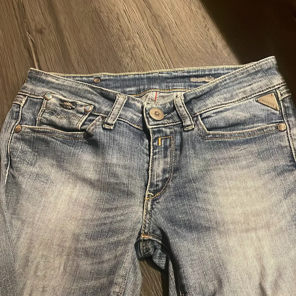 Säljer ett par snygga blå jeans med coola dragkedjedetaljer på bakfickorna. De har en klassisk femficksdesign och en lätt tvättad look som ger dem en avslappnad stil. Perfekta för vardagsbruk! Andvänd en gång . Jeans & Byxor.