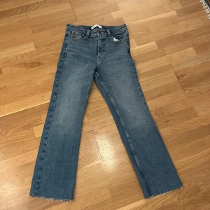 Blå jeans med fransar - Säljer ett par snygga blå jeans med fransar längst ner. De har en klassisk femficksdesign och en bekväm passform. Perfekta för en avslappnad stil!