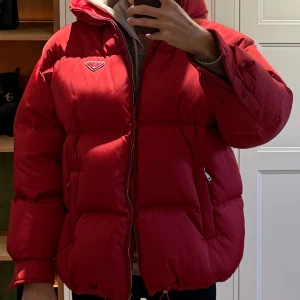 Prada Re-Nylon vinterjacka - Fantastisk Prada jacka i mörkare röd färg. Som ny! Inköpt i Sthlm på Prada, kvitto finns.  Storlek 38 men passar en 36/38