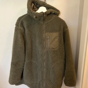 Grön teddyjacka/teddyfleece H&M - Grön teddyjacka/teddyfleece från H&M i strlk M. Oversized och något längre i modellen. Med luva och fickor.  Mycket skön och mysig.
