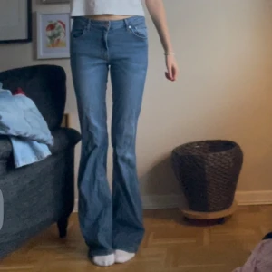 Blå bootcut jeans - Säljer ett par snygga blå midwaist bootcut jeans. De har en klassisk femficksdesign med dragkedja och knapp framtill. Perfekta för både vardag och fest!