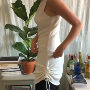 Asymmetrisk klänning - Finstickad asymmetrisk klänning från Nu-in! Går att knyta i sidorna till önskad längd/ stil. Storlek XS men skulle mer säga att den sitter som S-M