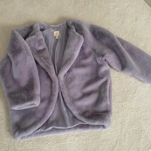Ljuslila pälsjacka från H&M - Säljer en supermjuk och fluffig ljuslila pälsjacka från H&M. Perfekt för att hålla sig varm och stilren under kyliga dagar. Jackan har en enkel design utan knappar eller dragkedja, vilket ger den en avslappnad look. Den är i storlek 38 och passar perfekt för både vardag och fest. 🦄💜