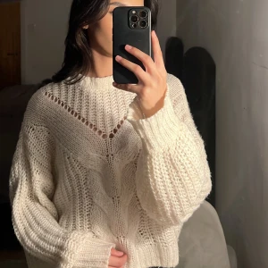 Vit stickad tröja - Säljer en supermysig vit stickad tröja med ett snyggt hålmönster. Den har långa ärmar och en avslappnad passform som är perfekt för kyliga dagar. Perfekt för både höst och vinter!