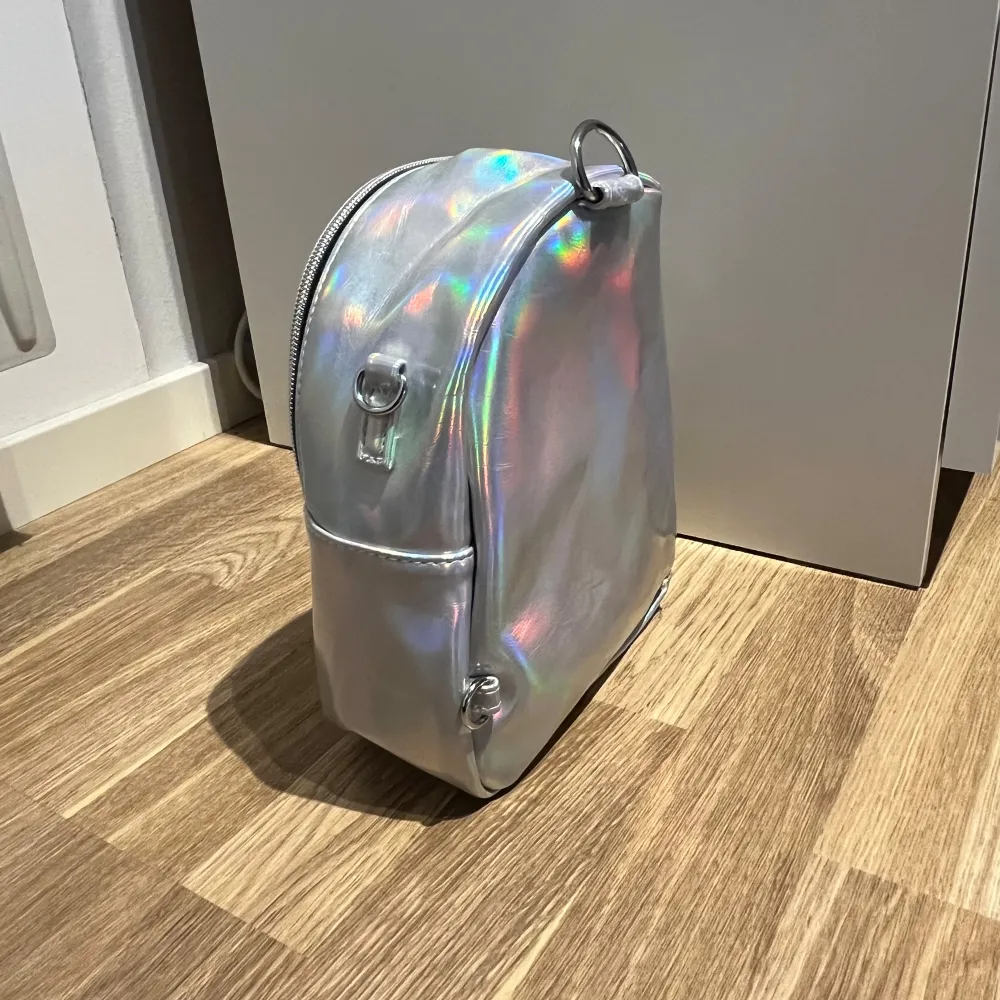 Säljer en supercool holografisk väska från Vans som går att använda som både ryggsäck och som crossbody. Nyskick då den nästintill aldrig är använd. Den har en praktisk dragkedja och en liten ficka framtill för extra förvaring. . Väskor.