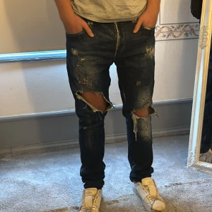 Philipp Plein jeans med slitningar - Säljer ett par coola Philipp Plein jeans i mörkblå denim. De har en massa slitningar och hål. Strl 32. Bra skick