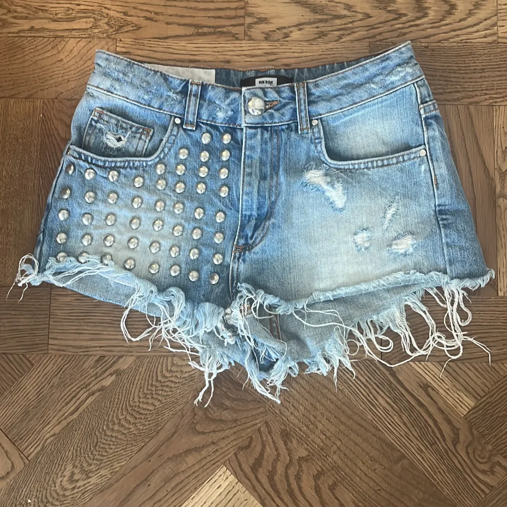 Säljer ett par coola jeansshorts från Bik Bok i storlek S. De är blå med nitar på ena sidan. Shortsen är Lågmidjade/ Mid rise. Midje bredden är 80 cm. . Shorts.