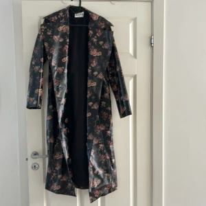 Lång kappa - Lång NA-KD regn kappa med blommor på jätte bra skick då den knappt är använd. Ny pris ca.900kr