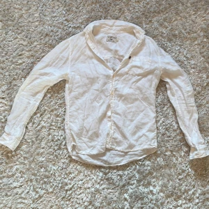 Vit linneskjorta från Lexington - Säljer en stilren vit linneskjorta från Lexington. Skjortan har långa ärmar och knappar framtill. Perfekt för en avslappnad men ändå snygg look. Passar bra till både vardag och fest! Saknar en knapp, därav priset!