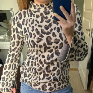 Stickad leopard tröja - Stickad tröja med leopardtryck. Fin passform med slits vid ärmarna. Liten polo