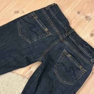 Mörkblå jeans med låg midja - Snygga mörkblå jeans med låg midja. De har dubbla knappar och dragkedja framtill. Märket är Lelles jeans och jag har sprättat en slits längst ner (bild 5) tveka inte på att kontakta för eventuella frågor eller fler bilder🩷🩷