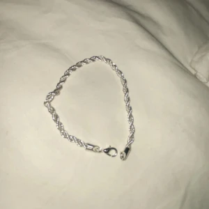 Silverfärgat armband - Snyggt silverfärgat armband med tvinnad design och karbinhakelås. Perfekt för att ge en elegant touch till din stil.