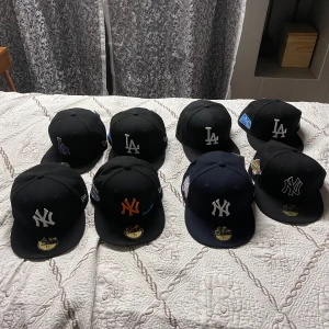 Svarta kepsar med broderade logotyper - Snygga svarta kepsar med broderade logotyper från olika lag. Kepsarna har platt skärm och finns med olika färgdetaljer som orange och lila. Perfekt för att visa ditt stöd för ditt favoritlag!Limited edition anniversary’s. 