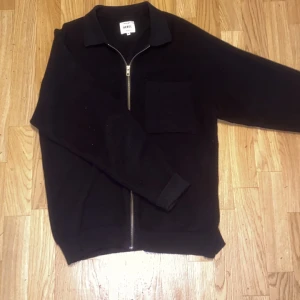 Overshirt - Säljer en stilren svart jacka från REBEL med dragkedja och en praktisk bröstficka. Jackan har en klassisk krage och är långärmad, perfekt för en avslappnad look.