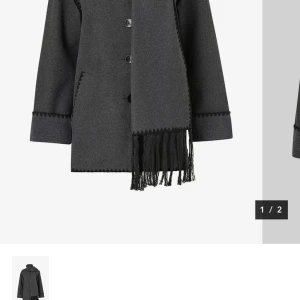 Grå kappa med fransdetaljer - Elegant grå kappa med knappar och matchande halsduk med fransar. Kappan har långa ärmar och dekorativa sömmar längs kanterna. Perfekt för kyliga dagar och för våren. Andvänd endast 2 gånger. Köptes för 999kr, säljer för 699. Pris kan diskuteras. 