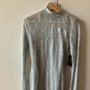 Glittrig ljusgrå klänning - Säljer en elegant ljusgrå klänning med glittrigt mönster. Det finns en ”under-klänning” i klänning. 