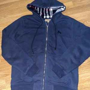 Burberry hoodie mörkblå - Säljer en snygg mörkblå hoodie från Burberry. Perfekt för en stilren och bekväm look. Endast använd 3 gånger och är i nyskick. Har du några frågor så är det bara att höra av sig.
