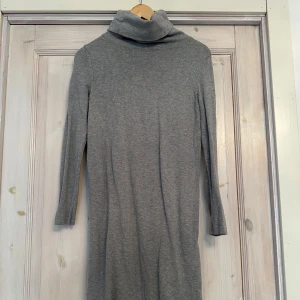 Grå poloklänning - Säljer en stilren grå poloklänning med långa ärmar. Perfekt för kyligare dagar med sin mjuka och bekväma passform. Klänningen har en klassisk design som passar till många tillfällen. Storlek XS.