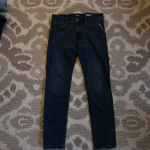 Mörkblå jeans från Replay - Snygga mörkblå jeans från Replay med klassisk femficksdesign och knappgylf. Perfekta för en stilren look. Märkeslapp i läder baktill.