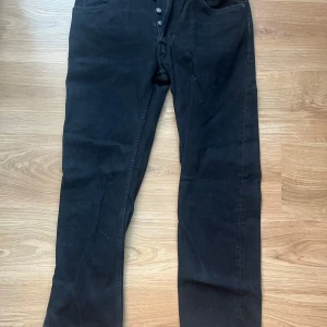 Svarta straight jeans från Zara - Snygga svarta straight jeans från Zara i modellen Nordics Straight. De har en klassisk design med knappar i gylfen och är perfekta för en stilren look. Passar bra till både vardag och mer uppklädda tillfällen.