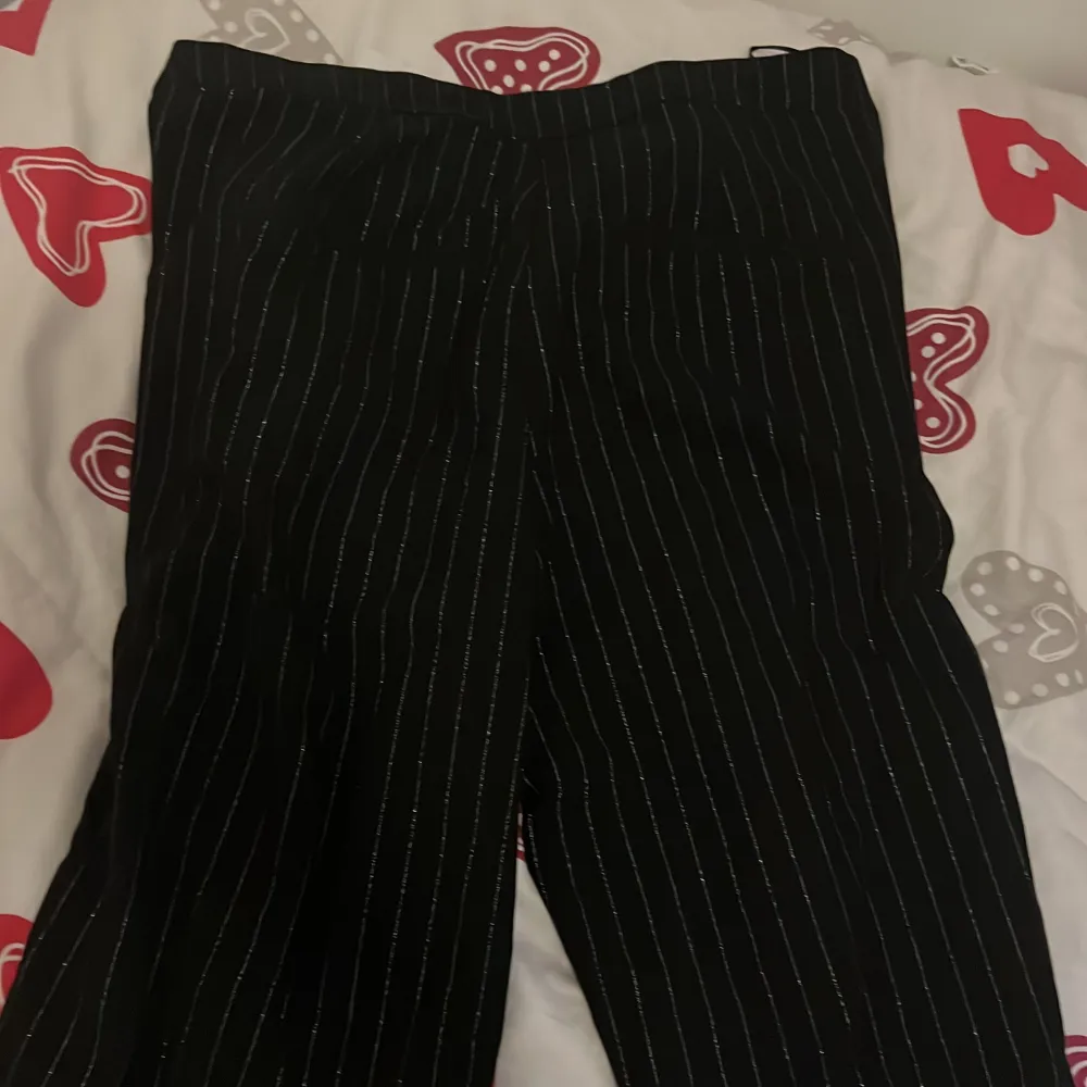 Snygga svarta byxor från Vila med vita ränder. Byxorna har en elegant design och är perfekta för en stilren look. De är tillverkade i ett bekvämt material och har en elastisk midja för extra komfort. Hör av dig vid intresse (aldrig använt). Farkut & Housut.