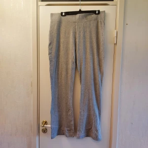 Grå utsvängda byxor/yogapants  - Bekväma grå flare-byxor/yogapant från Seasons i storlek L. Byxorna har en loose passform och är tillverkade i mjukt material, perfekt för avslappnade dagar. De har en hög midja och en subtil broderad detalj på sidan. Normal längd