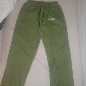 Byxor - Säljer ett par gröna tunna mjukisbyxor från AUSSUP. Byxorna har en elastisk midja med snörning och är perfekta för en avslappnad stil. De är tillverkade i ett mjukt material som ger en bekväm passform.