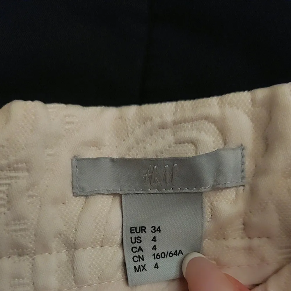 Snygg beige kjol från H&M med ett subtilt mönster i tyget. Kjolen har en klassisk A-linjeform och är perfekt för en stilren look. Den är i storlek 34 och passar perfekt för dig som gillar en elegant stil.. Hameet.