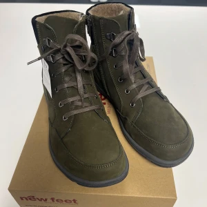 Khaki boots från New Feet - Damkängor med snörning och blixtlås från New Feet. Pikosfoder med vattenavvisande membran. Yttersula i TR. Löstagbar 6mm stötdämpande innersula. Helt nya med prislapp i orginal kartong. Tillverkade i Danmark. Nypris 2050kr. Storlek 40.
