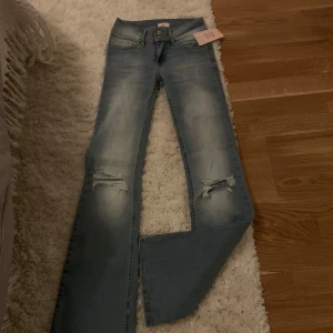 Ljusa jeans med slitningar från Nelly - Snygga ljusblå jenas från Nelly, trendiga med hål på knäna. ALDRIG använda pga av fel storlek och går inte att lämna tillbaka. Köpta för 700 kr