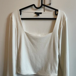 Vit långärmad topp från Amisu - Säljer en stilren vit långärmad topp från Amisu. Toppen har en fyrkantig urringning och är tillverkad i ett mjukt material som ger en bekväm passform. Perfekt för både vardag och speciella tillfällen.