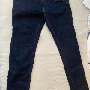 Mörkblå jeansbyxor - Snygga mörkblå jeans med en klassisk femficksdesign och knappgylf. De har en rak passform och är perfekta för en avslappnad stil. Midjan är märkt W33 L32, vilket ger en bra indikation på storleken.