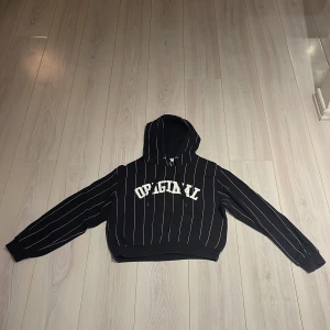 Svart och vit randig hoodie från H&M Divided - Säljer en svart hoodie från H&M Divided med vita ränder och texten 'ORIGINAL' på framsidan. Den har en klassisk huva och långa ärmar, perfekt för en avslappnad stil. Den har storlek M och det motsvarar 170 cm i storleken! Passar bra till jeans eller joggers samt även de flesta stilarna ✅