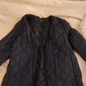 Mörkblå quiltad jacka från Uniqlo - Säljer en mörkblå quiltad jacka från Uniqlo i storlek XS.  Skulle säga att den passae xxs-s. Jackan är varm och vadderad, perfekt för typ alla väder. Den har en stilren design med knappar framtill och är tillverkad i syntetmaterial. Använd men inget som syns. Nypris ungefär 800 mitt pris 550 (kan diskuteras vid snabb affär) man kan också få plats med hela jackan i en liten påse spm ligger i en av innerfickorna