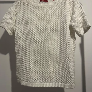 Vit stickad kortärmad tröja - Säljer en vit stickad tröja med korta ärmar. Tröjan har ett fint, luftigt stickmönster som ger en skön och avslappnad känsla. Perfekt för vår och sommar!