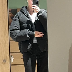 Svart pufferjacka med huva - Säljer en svart pufferjacka med huva och dragkedja. Jackan har en oversized passform och långa ärmar, perfekt för kyliga dagar. Den är i storlek S och den är ifrån pull and bear. Skriv gärna för fler frågor!
