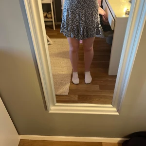 Blommig kjol - Söt blommig kortkjol med volang, blå med vita blommor. Från lager157, storlek S. Knappt använd.