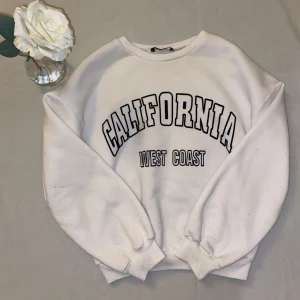 Vit sweatshirt med tryck - Säljer en vit sweatshirt med texten 'California West Coast' i svart i storlek S (EU:36), den är mjuk och skön inuti💕. Pris kan diskuteras 🩷